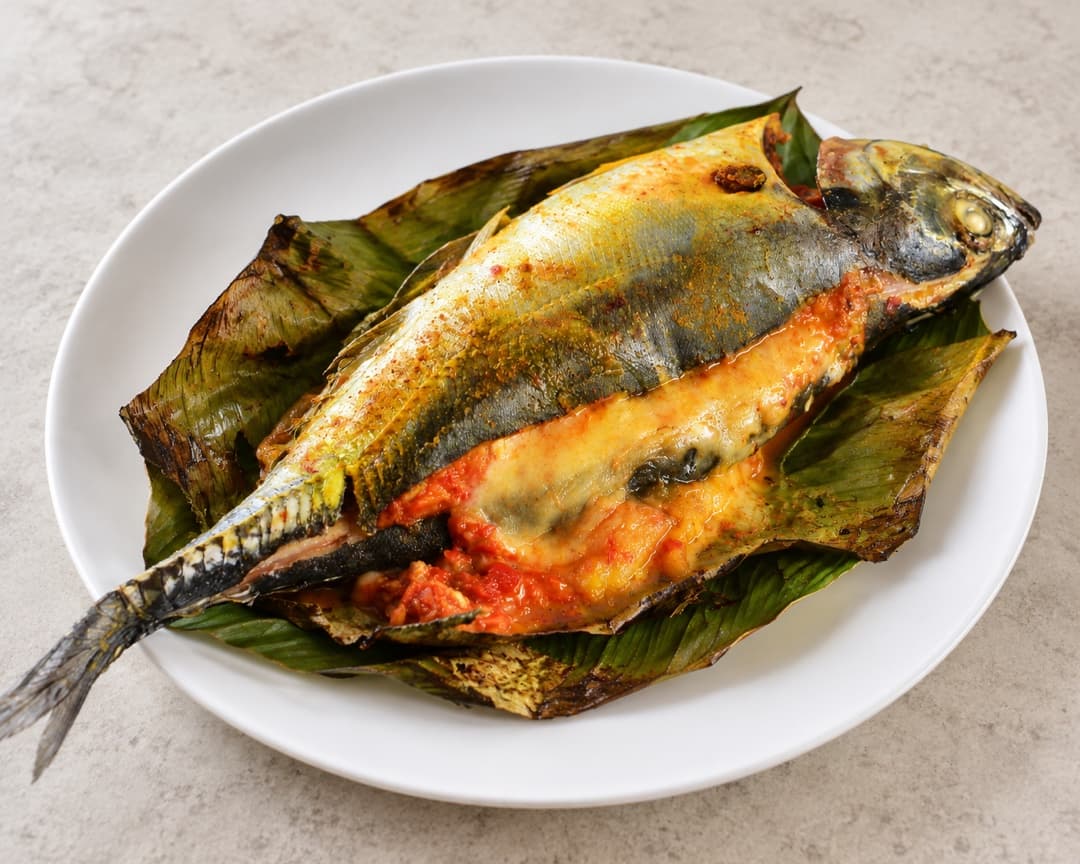 Whole cheesy ikan sumbat cili stuffed fish on a banana leaf